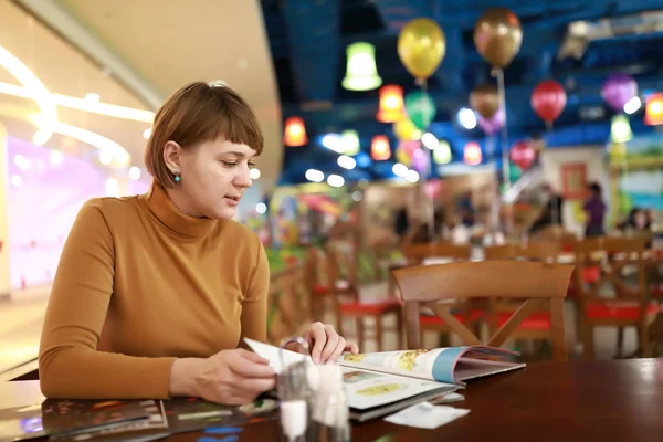 Woman choosing dish in menu — Stockfoto