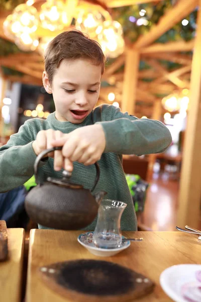Ребенок наливает чай в турецкое стекло — стоковое фото