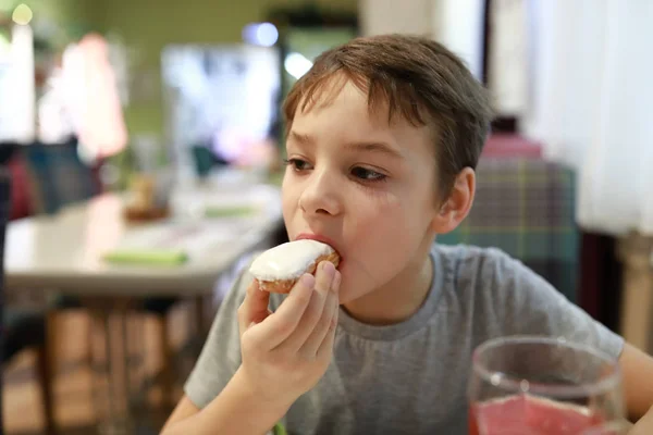 Boy eating vanilla eclair — Stock Photo, Image