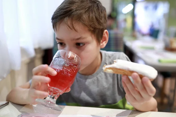 Niño tiene jugo con eclair — Foto de Stock