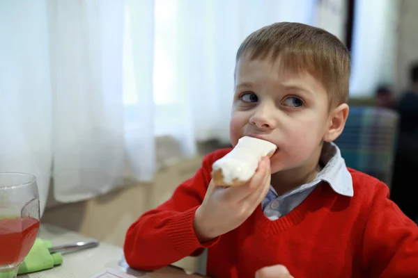 Ragazzo che mangia eclair vaniglia — Foto Stock