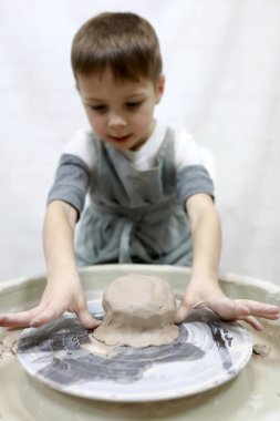 Çocuk çanak çömlek tekerinde çalışıyor.