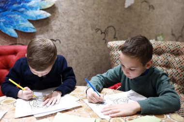 Çocuklar kalemle resim yapar.