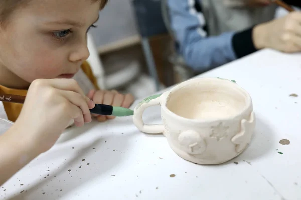 Boy painting clay mug — ストック写真