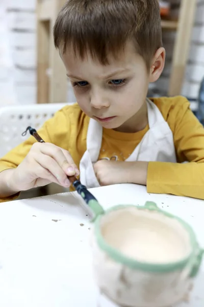 Boy paints clay pot — Stock Photo, Image