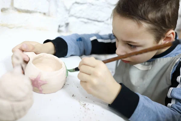 Child painting clay cup — Stock Photo, Image