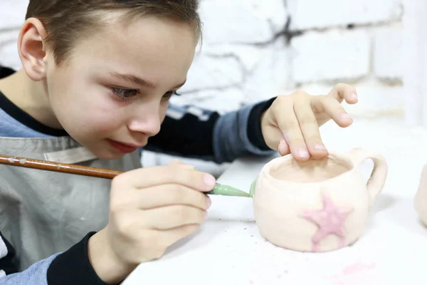 Child painting clay mug — Stock Photo, Image