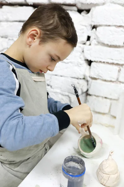 Child paints clay mug