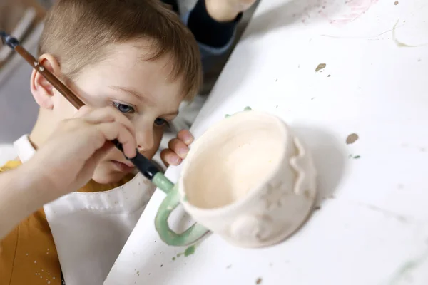 Kid painting clay mug — Stock Photo, Image