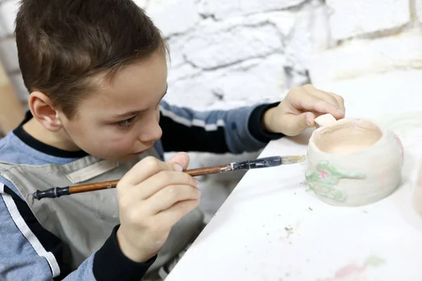 Малыш рисует глиняную чашку — стоковое фото