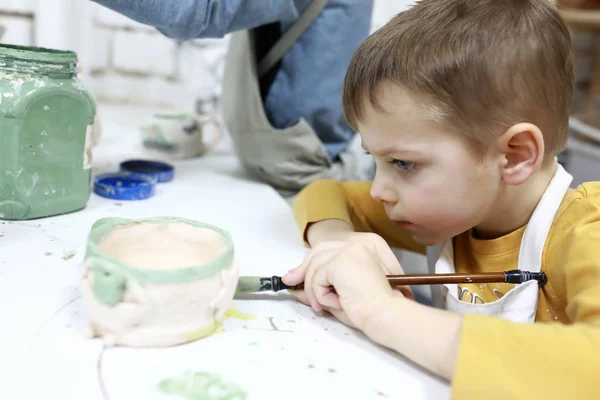 Kid paints clay mug — Stock Photo, Image
