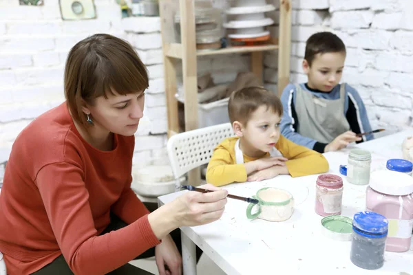 母亲和儿子在陶器作坊里画黏土杯 — 图库照片