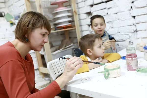 Oğulları olan anne kilden tencere boyar. — Stok fotoğraf