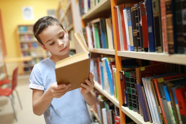 Criança escolhendo livro na biblioteca — Fotografia de Stock