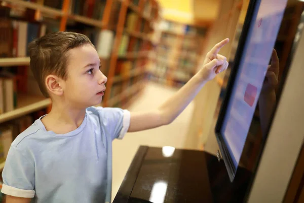 Niño eligiendo libro usando pantalla táctil —  Fotos de Stock