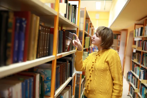 Mujer eligiendo libro en biblioteca — Foto de Stock