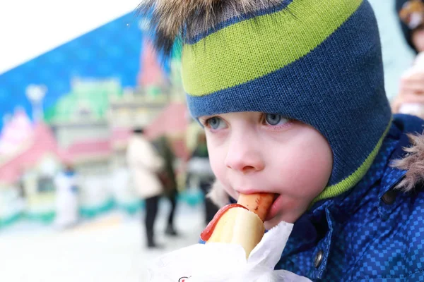 Kind eet hotdog op straat — Stockfoto