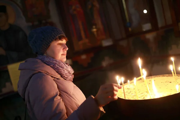 Woman lights candle in church — Stockfoto