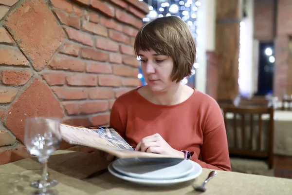 Žena se dívá do knihy menu — Stock fotografie