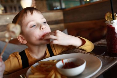 Çocuk restoranda parmaklarını yalıyor.