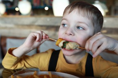 Çocuğun restoranda et ve sebze kebabı var.