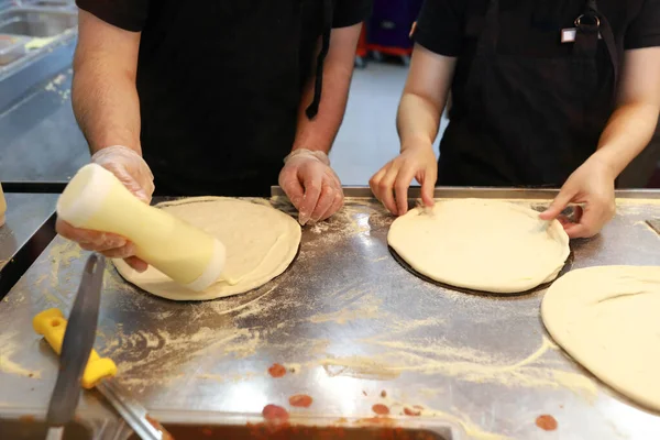 Two chefs preparing pizza for baking at Pizzeria