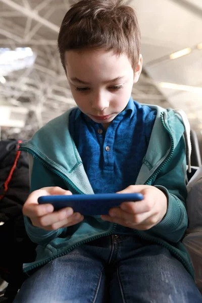 空港の出発ラウンジでスマートフォンを遊んでいる子供 — ストック写真