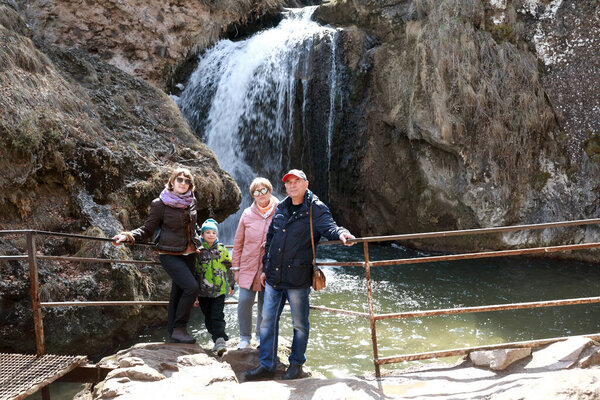 Family on background of Honey waterfall in river gorge Alikonovka, Kislovodsk, Russia