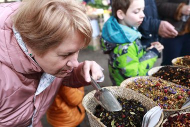 Yaşlı kadın markette çay kokluyor.