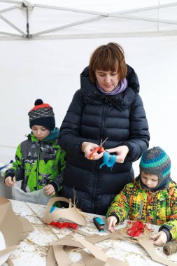 Anne ve iki oğlu dışarıda karton işçiliği yapıyorlar.