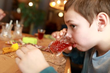 Çocuk restoranda ambar çayı içiyor.