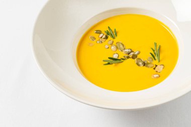 Beyaz arka planda balkabağı kremalı çorba.