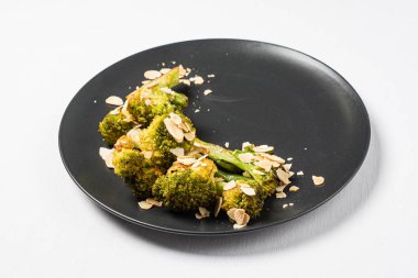 Siyah zemin üzerinde badem olan kızarmış brokoli.