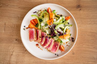 Taze salata ve ahşap arka planda ton balığı bifteği.