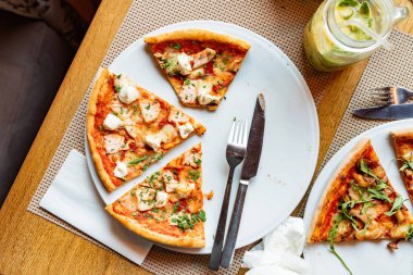 Arkadaşlar kapalı kafede pizza yiyorlar.