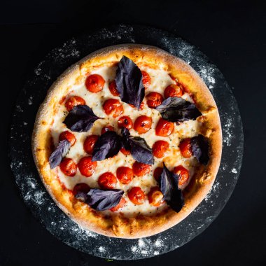siyah arka plan üzerine kiraz domates ile lezzetli pizza