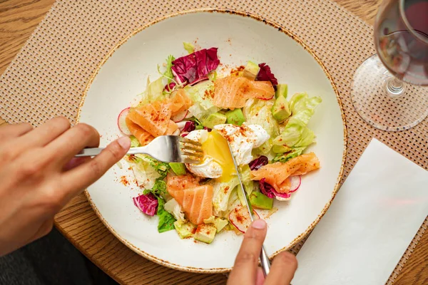 man eating salad with salmon and poached egg