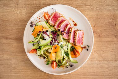 Taze salata ve ahşap arka planda ton balığı bifteği.