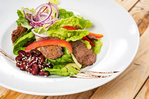 salad with beef, red beans and vegetables, wooden background