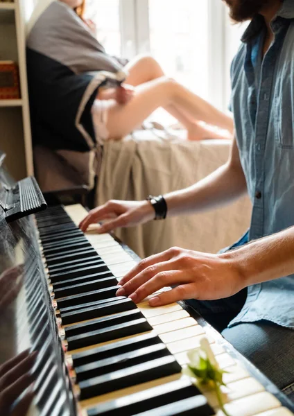 男人坐在公寓的客厅里弹钢琴 — 图库照片