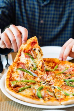 Kafede İtalyan pizzası yiyen bir adam.