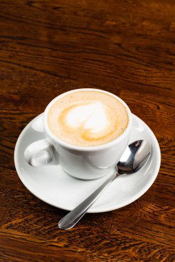 Tahta masada kalp şeklinde kapuçino.