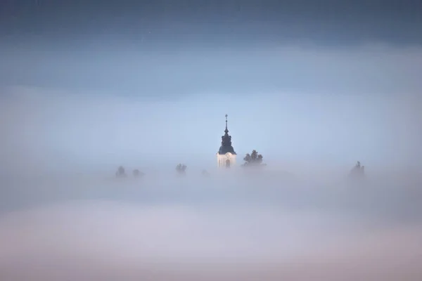 Iglesia escondida en la niebla de la mañana — Foto de Stock
