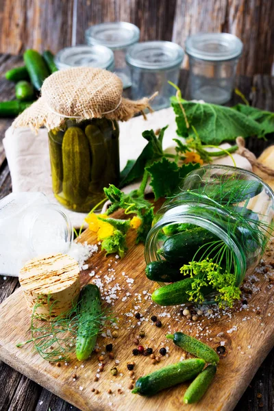 Jars of pickled marinated cucumbers on wooden board