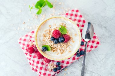 Yoğurt böğürtlen, ahududu ve yulaf gevreği kırmızı grafik üzerinde ile havlu karar verdi.
