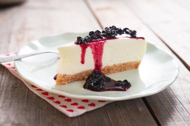 ahşap masa üzerinde yaban mersinli cheesecake