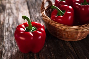 Ahşap arka plan üzerinde sepet ile taze kırmızı biber