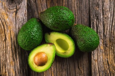 Avocados on wooden background clipart