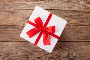 Eski tahta üzerinde kırmızı bir yay ile beyaz kutu