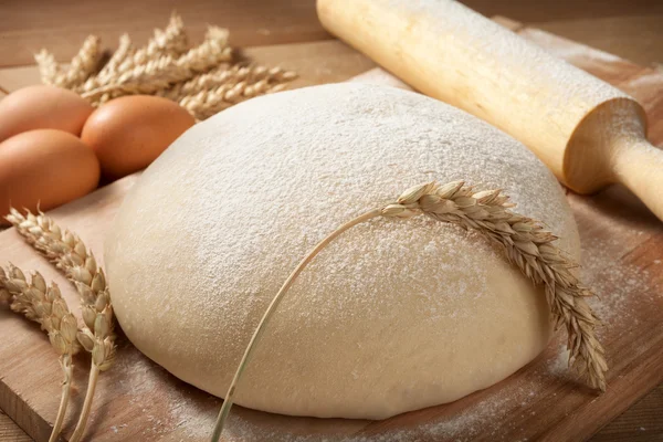 La masa fresca a la tabla con las espigas del trigo y el rodillo . — Foto de Stock